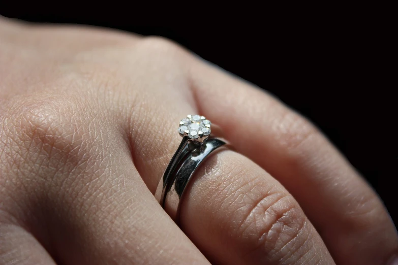 woman's hand displaying an engagement ring with a diamond