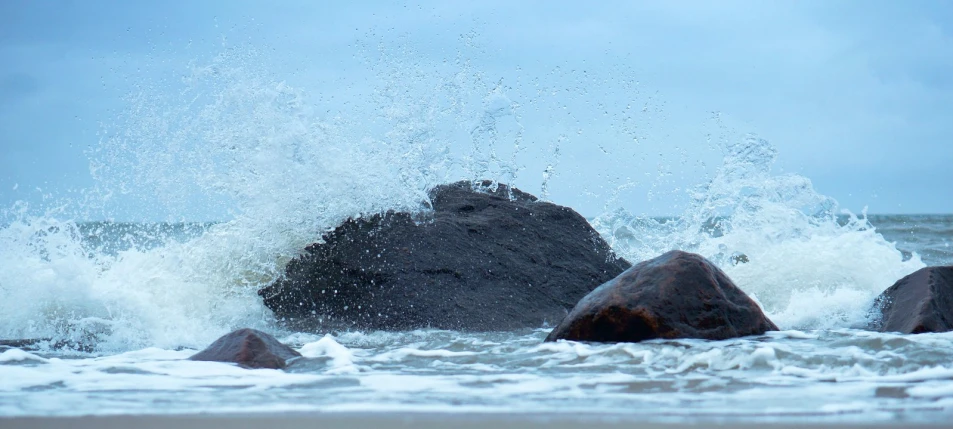 a wave hitting on large rocks in the ocean