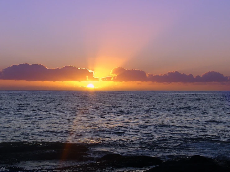 the sun set over an ocean with waves