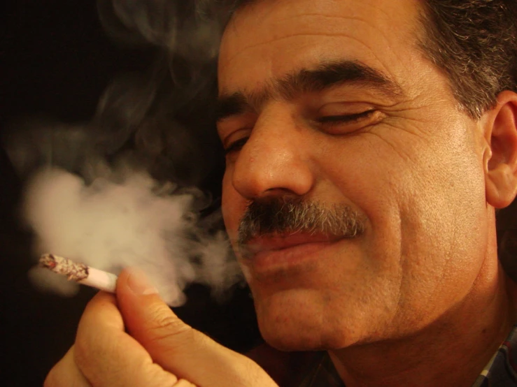 a man smoking a cigarette with his right hand resting on his mouth