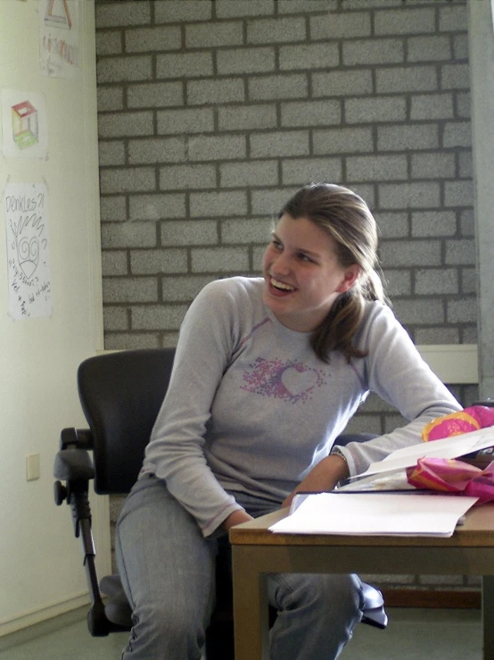 a woman sitting at a desk with some books and a camera