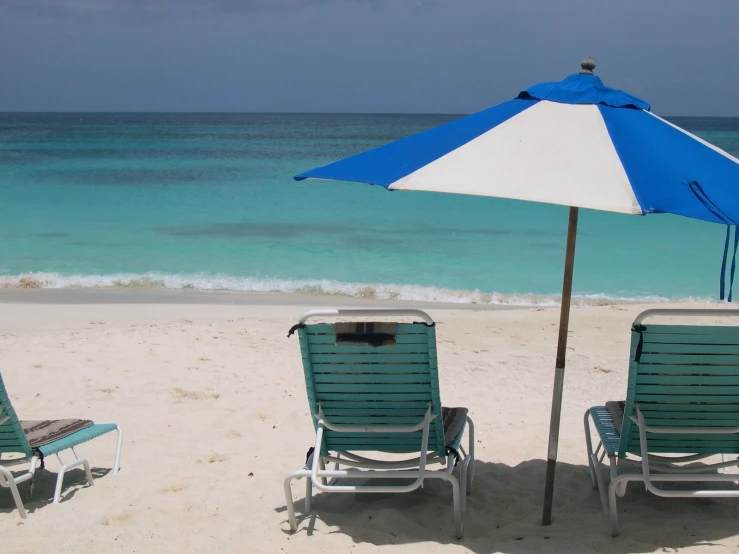 two lawn chairs and an umbrella on the beach