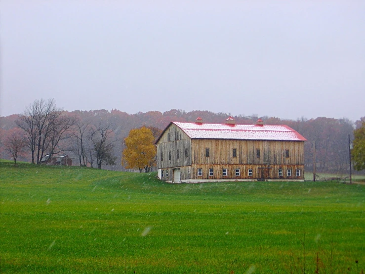 a barn sits in a green pasture in the fall