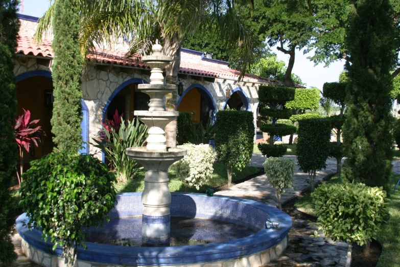 a fountain surrounded by different trees and bushes