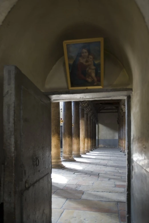 the interior of a building that has pillars and a painting