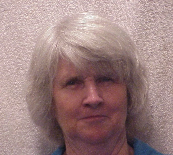 a white woman with light grey hair wearing a blue shirt