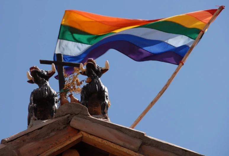 a statue stands in front of a colorful flag