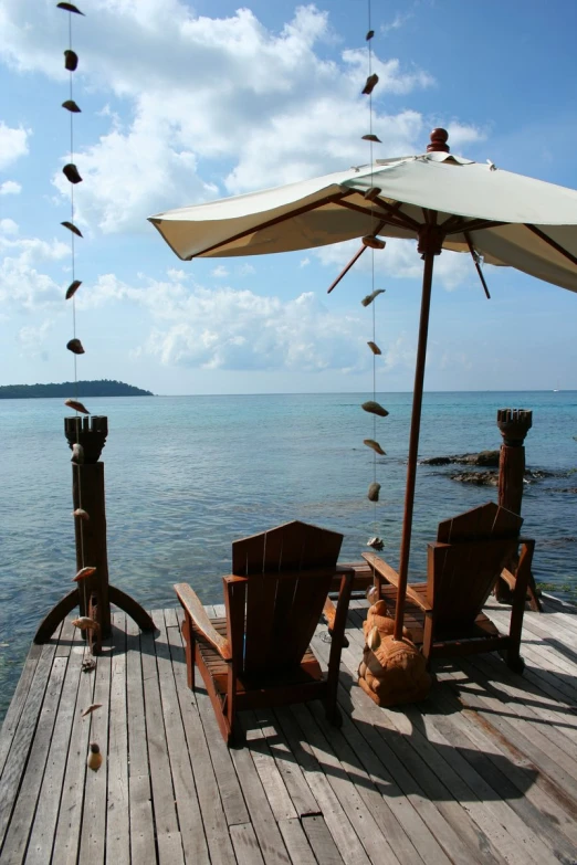 birds flying over chairs on the edge of a pier