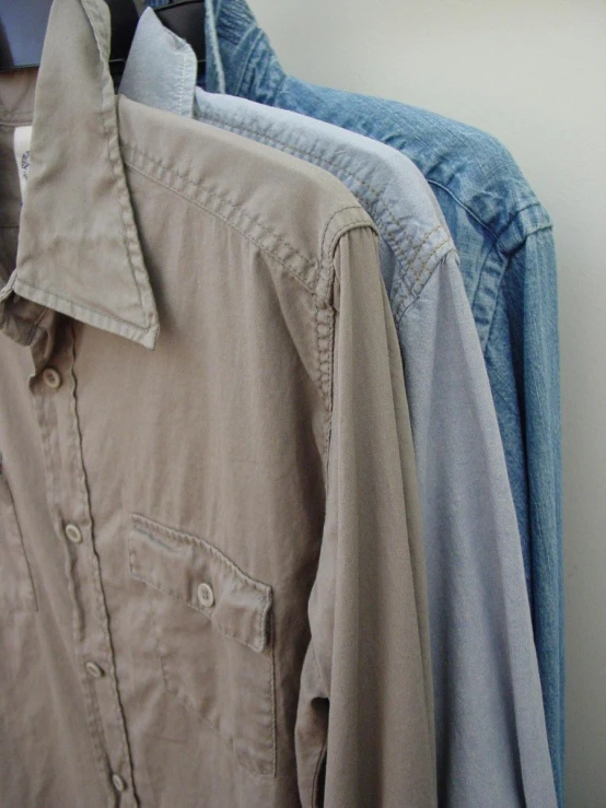 shirts hanging up against the wall on clothes hangers