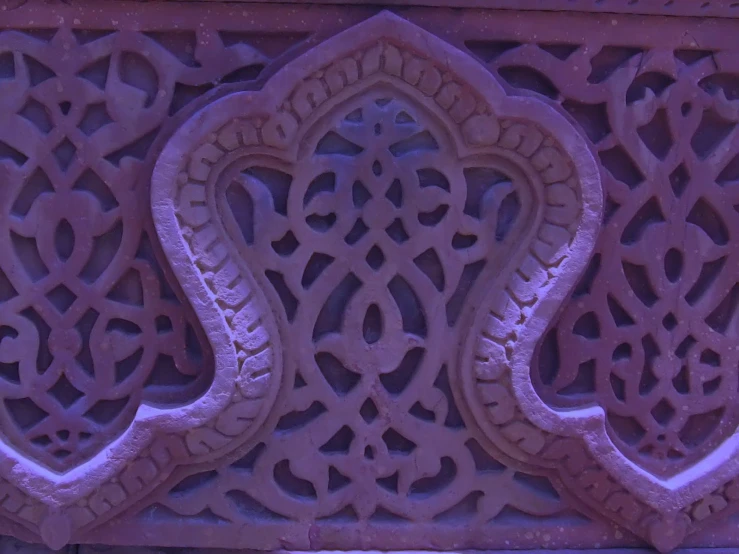 an ornate design on a fence with a bird sitting behind it