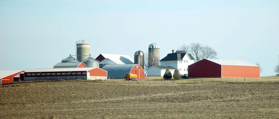 an old barn sits in the distance behind some grain silos