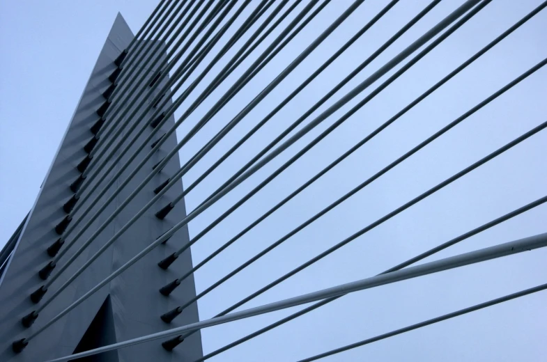 looking up at the side of a bridge that has lines and poles