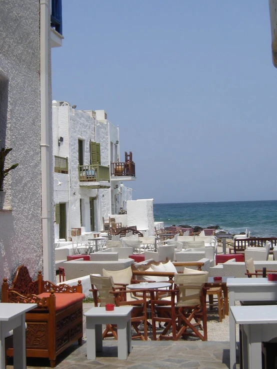 some tables and chairs by the ocean in a city