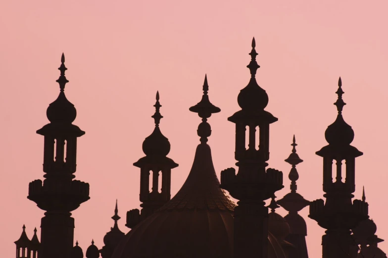 silhouettes of ornately styled structures against a pink sky