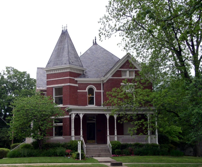 an ornate building with two floors, four windows and a steeple, in front of the trees