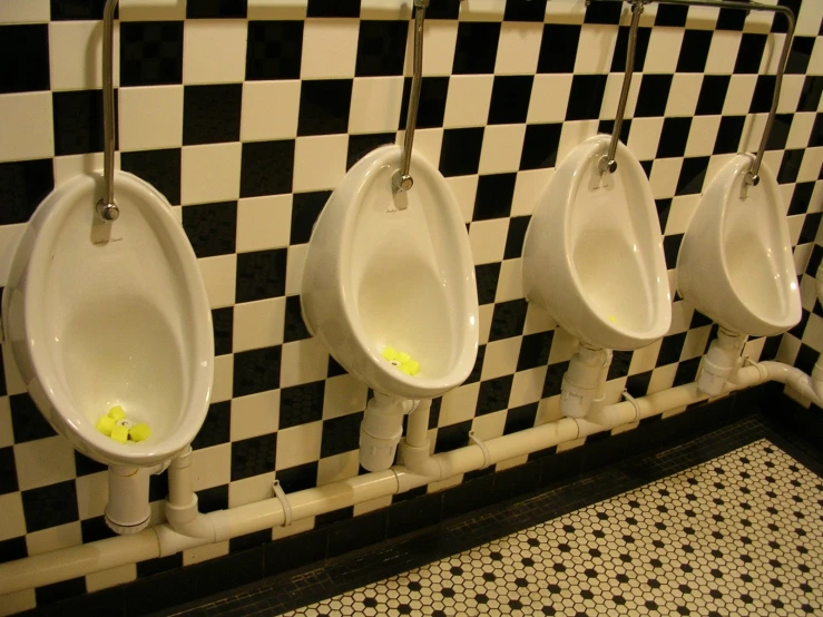 four urinals on black and white checkered wall