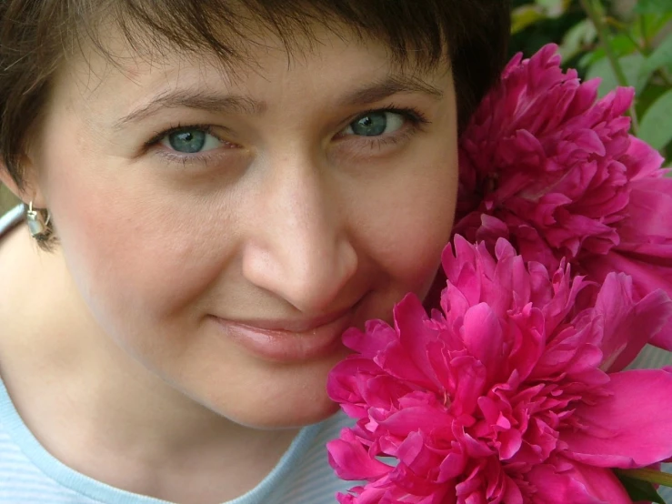 a young lady smiling and holding a flower