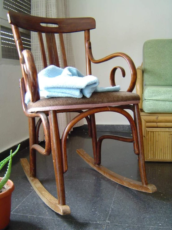 a small wooden rocking chair with a towel on it