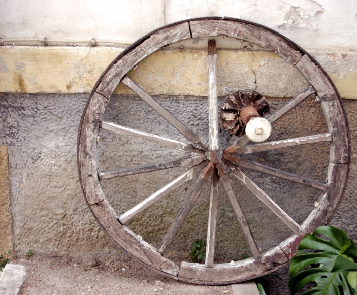an old weathered wheel in front of a wall