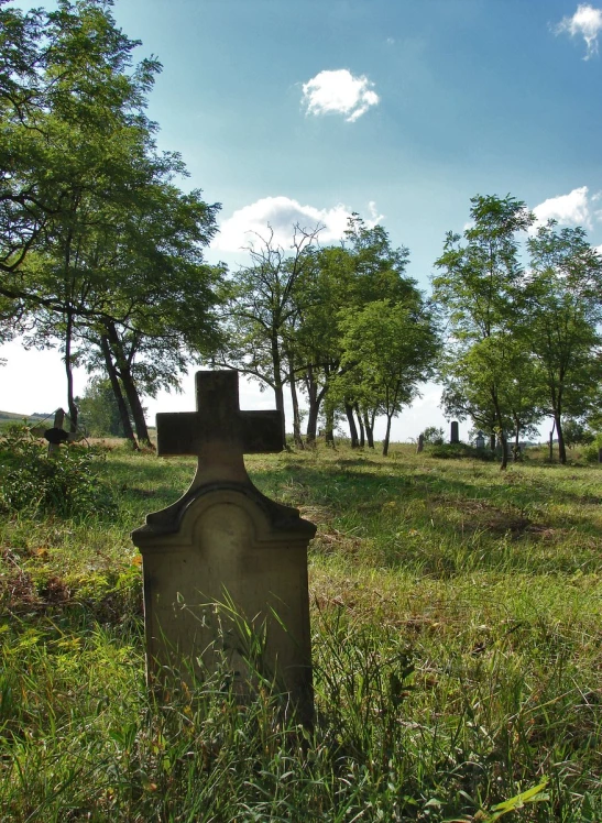 a cemetery sits in the middle of a green grass covered meadow