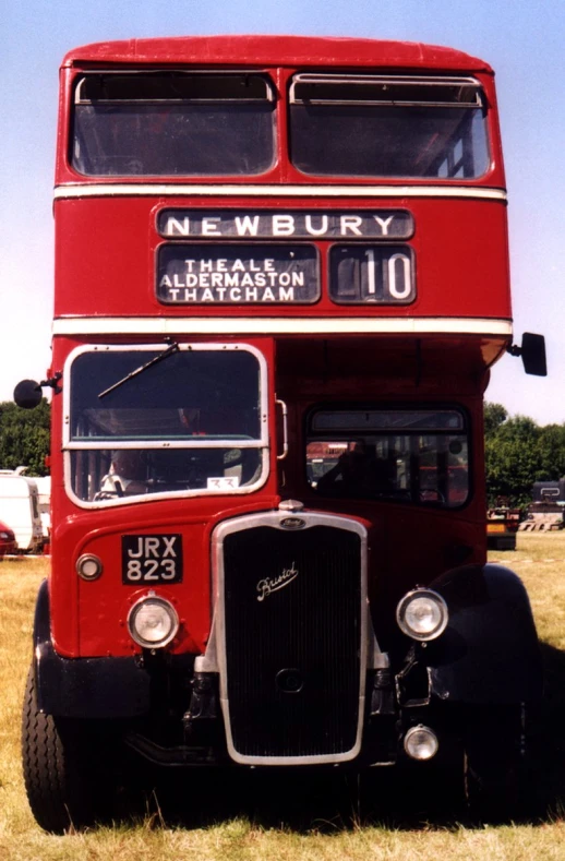 a red double decker bus on display in a field