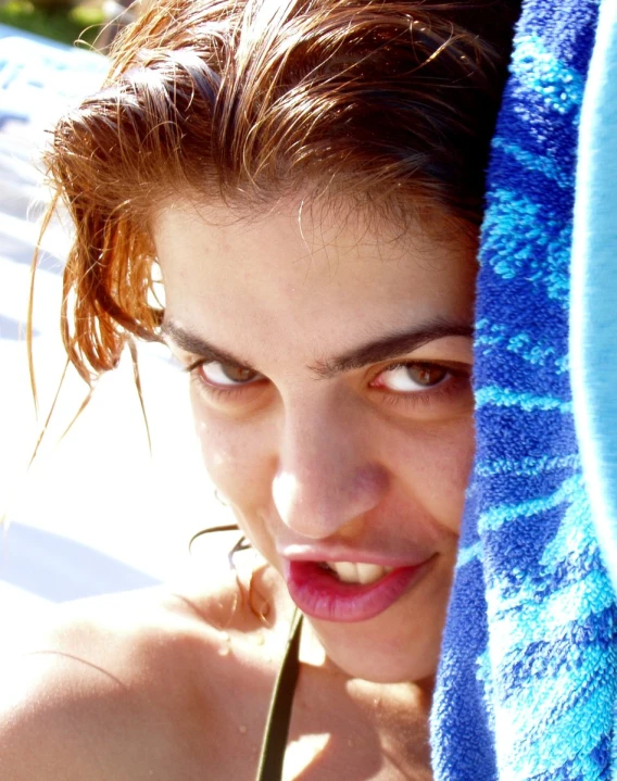 a beautiful young lady holding onto a towel and looking at the camera