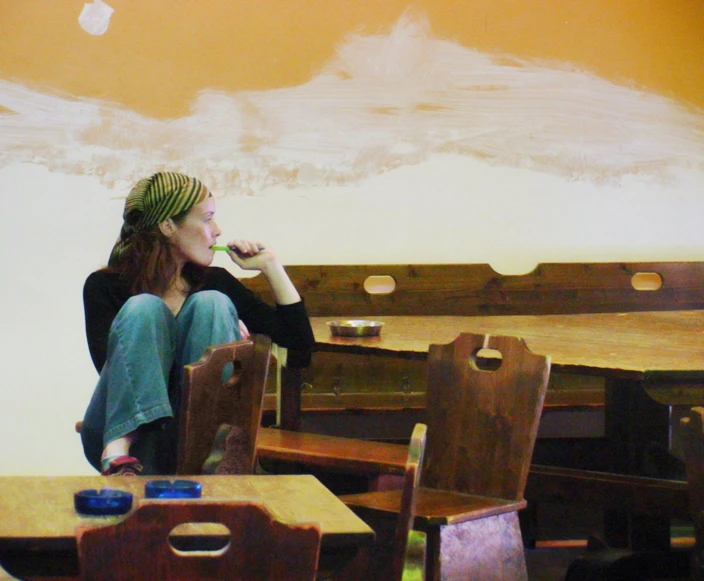 a woman sits alone in a restaurant while she is drinking