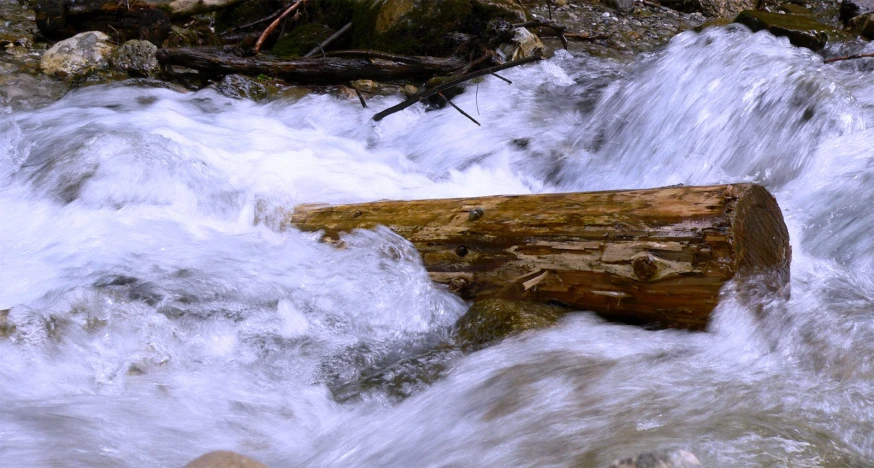 a log sitting on the side of a waterfall