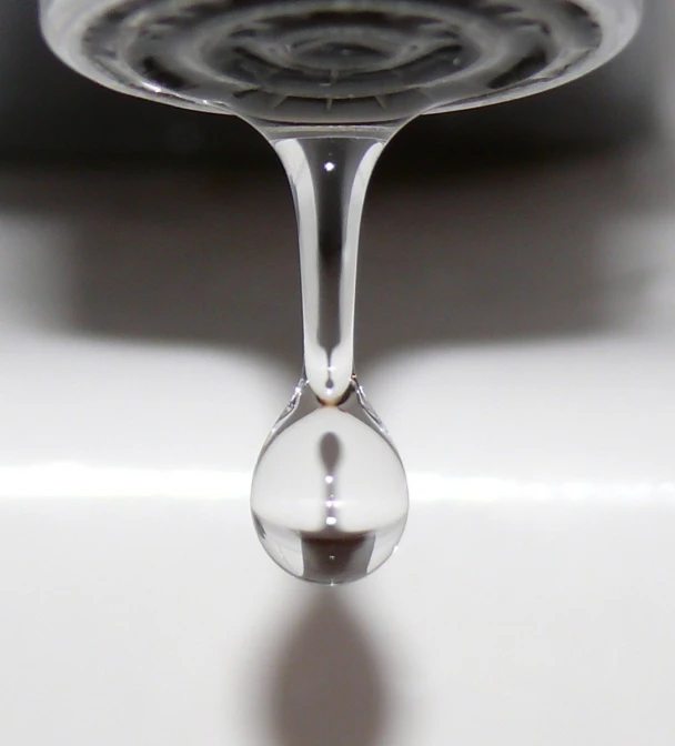 a drop of water is hanging from a faucet