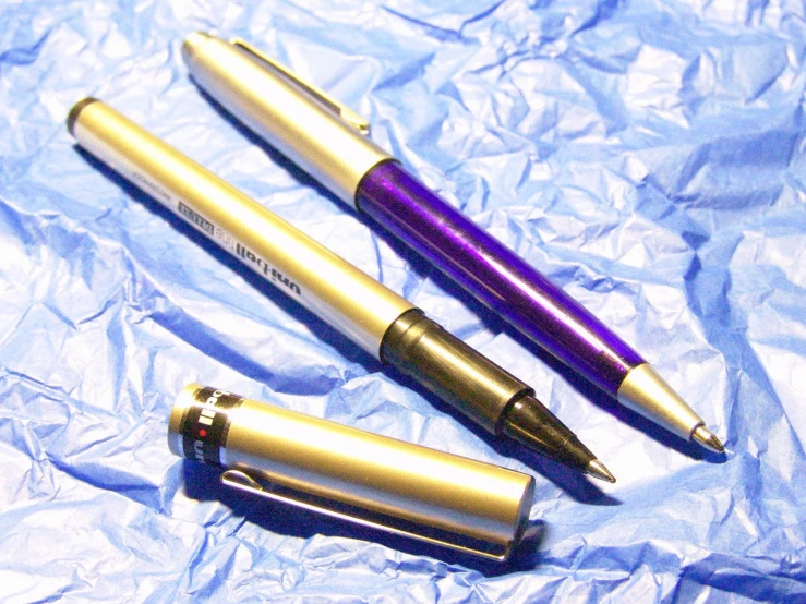 three fountain pens are lying on some paper