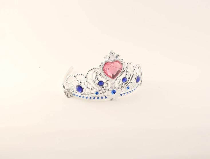 a silver metal tiara with pink stone and blue sapphires