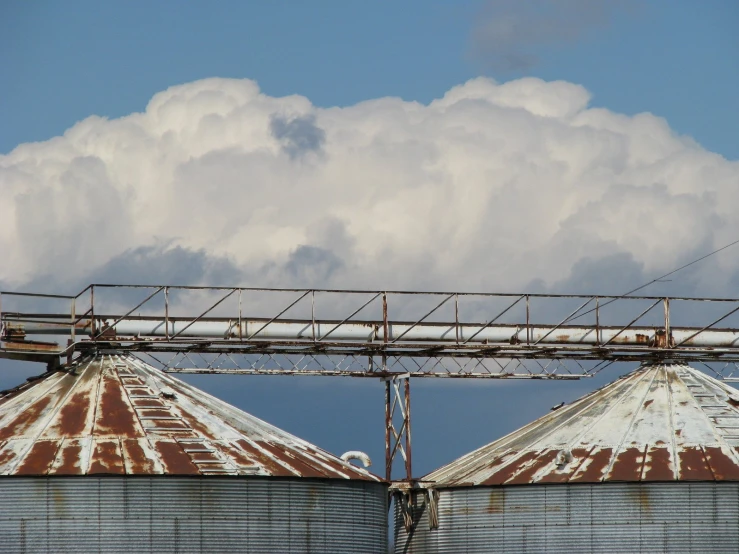 an old metal silo with clouds behind it