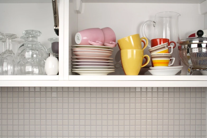 dishes and cups sitting on a shelf inside the kitchen