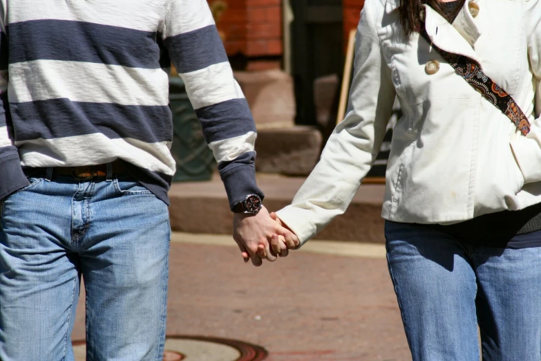 two people hold hands on the sidewalk in front of the building