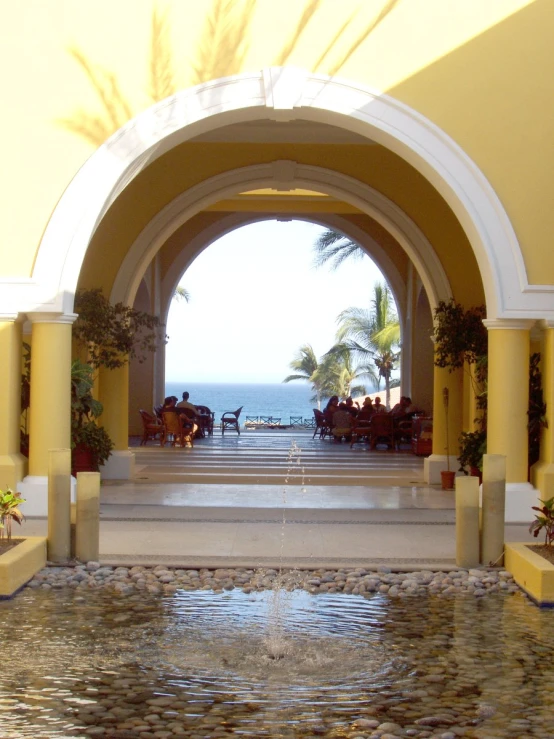 a large archway with a fountain in front of the ocean