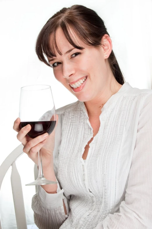 a woman holding up a glass of red wine