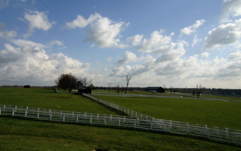 a beautiful country field surrounded by a white picket fence