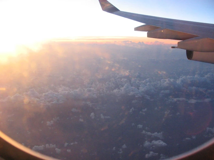 a view out an airplane window at the sun