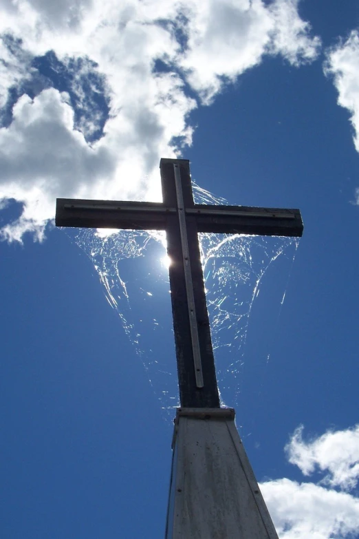 a cross is illuminated against the bright sky