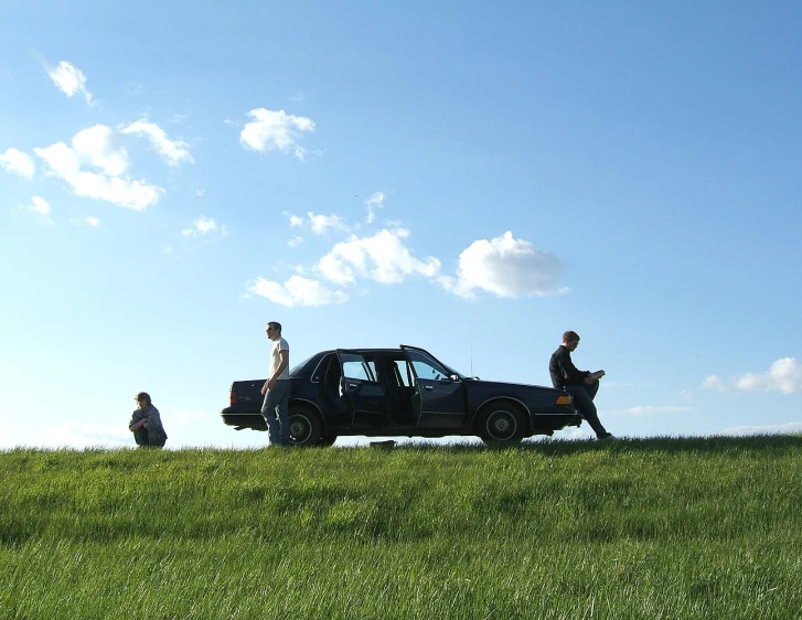 three men walking and sitting next to their vehicle