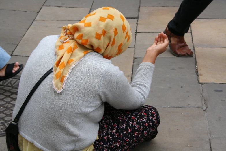 two people standing over sitting on a sidewalk