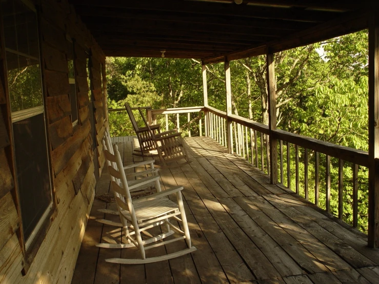 some rocking chairs are lined up on the porch