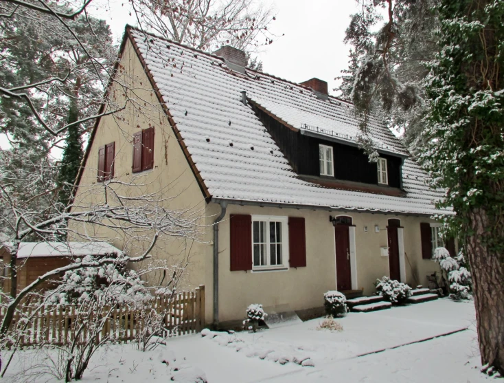 a house with red shutters and a white roof is covered in snow