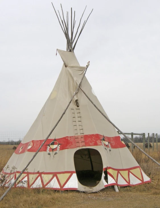 an indian teepee in a field, a red and white sign that reads indian war
