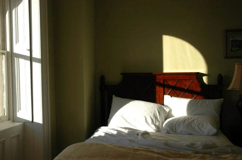 a bedroom with green walls, two large windows and white bed linens