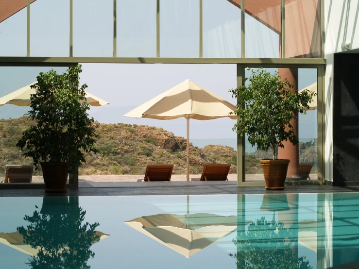 an open, airy looking swimming pool with tables and umbrellas