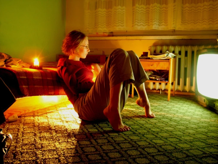 a woman is sitting on the floor watching television