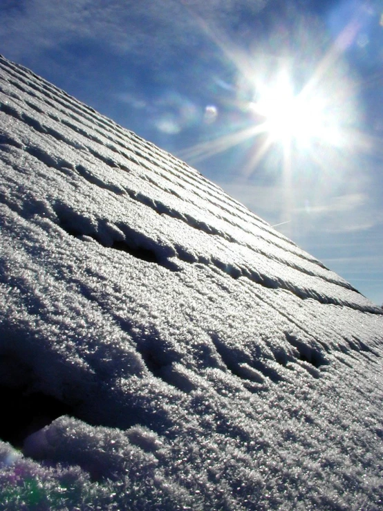 snow on the slopes are blowing off a bright blue sky