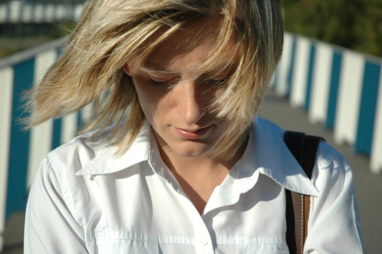 a woman in a white shirt is looking at her cellphone