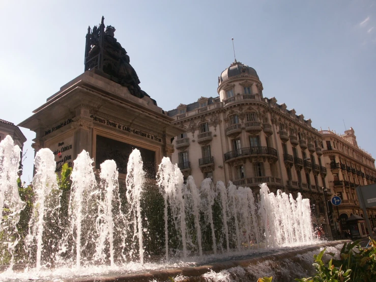 fountains in a plaza with buildings and trees